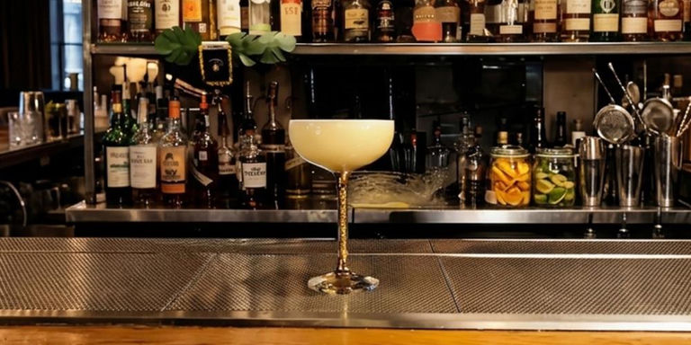 Amaretto sour cocktail in sparkling stem coupe glass with frothy egg white top