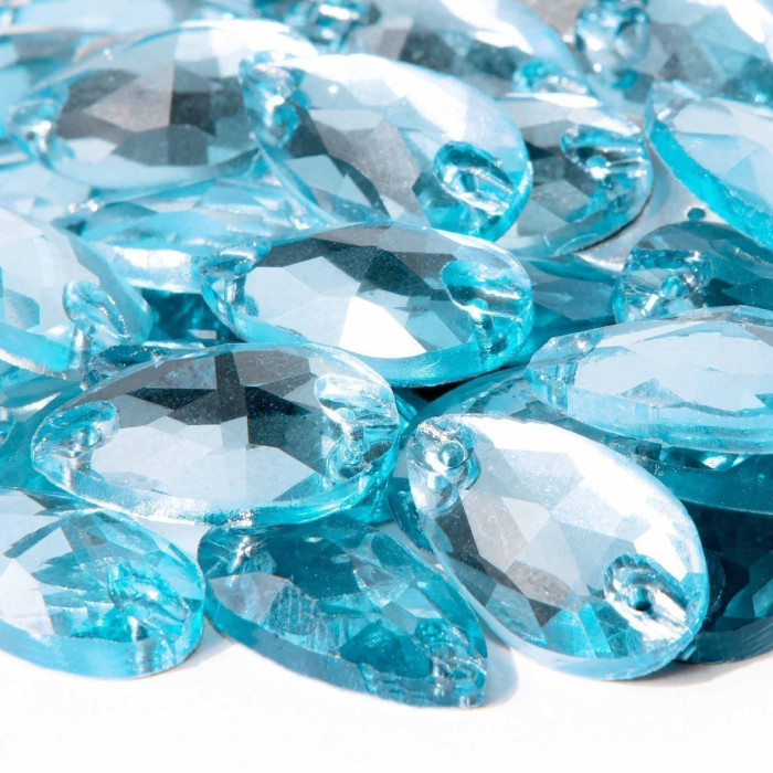 Aqua teardrop-shaped rhinestones with faceted surfaces and small holes for sewing arranged closely together.