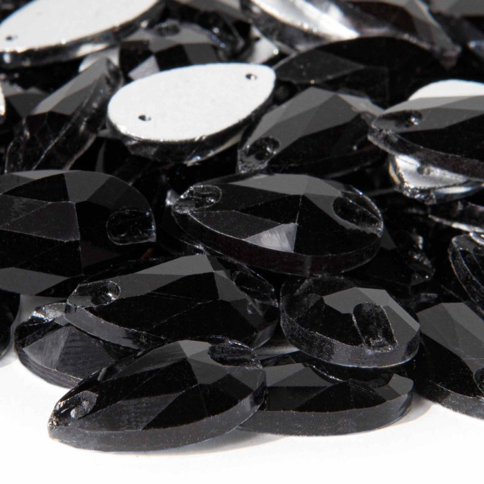 Black teardrop-shaped rhinestones with faceted surfaces and small sewing holes arranged in a scattered pile.