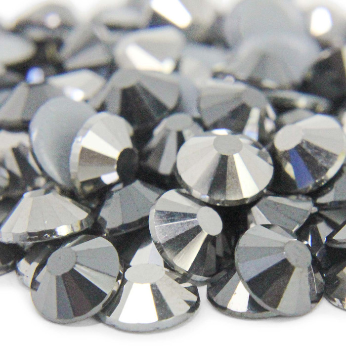 Machine cut crystal rhinestones in jet hematite featuring a faceted surface and gray glue backing with a reflective finish.
