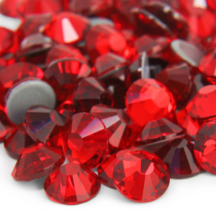 Red machine-cut crystal rhinestones with faceted surfaces and gray glue backing varying in size and shape.