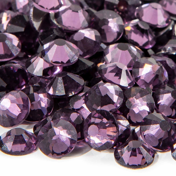 A pile of purple flatback rhinestones with 12-16 facets featuring a silver metal backing and a glossy finish.