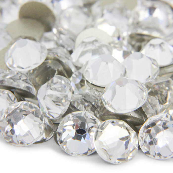 Clear multi-faceted rhinestones with a shiny surface varying sizes and a reflective quality arranged in a scattered pile.