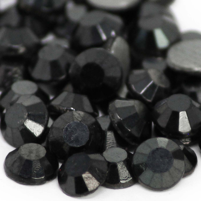 Faceted round jet hematite rhinestones in varying sizes glossy black with gray glue backing reflecting light with sharp edges.