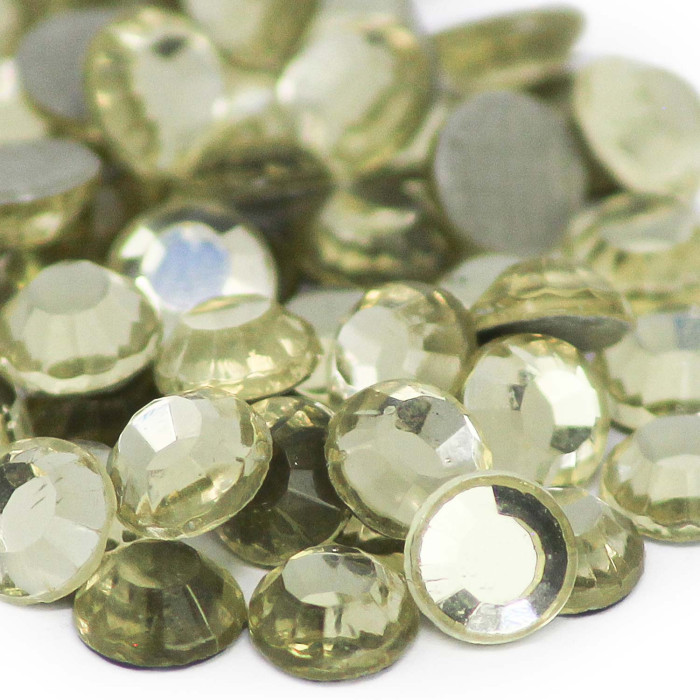 Machine cut crystal rhinestones in pale yellow with faceted surfaces and gray backing varying in size and slightly different shades.