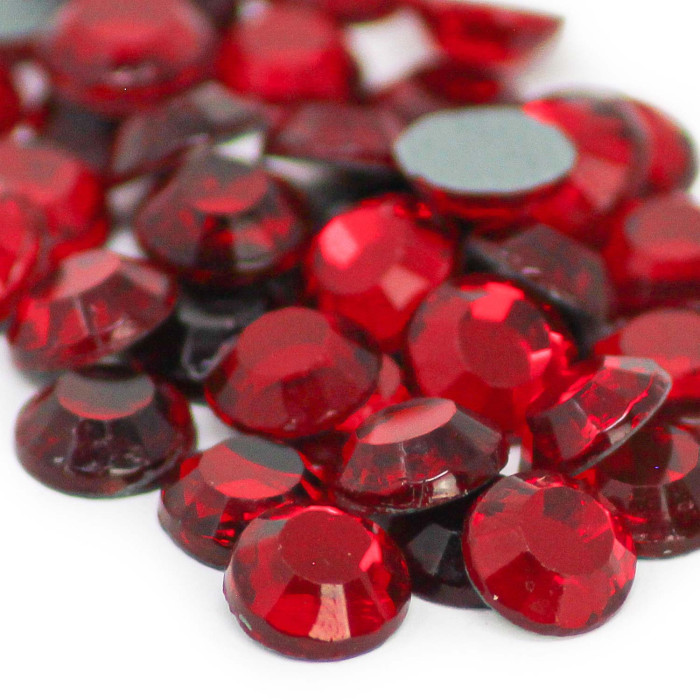 Red machine-cut crystal rhinestones with faceted surfaces some with gray glue backing in various sizes and shapes.