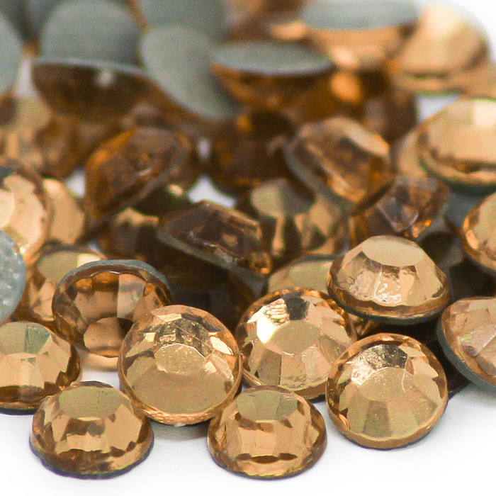 Machine cut crystal rhinestones in amber and light gray faceted with a flat backing and slight color variations.
