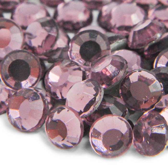 Faceted round glass stones in light amethyst featuring a smooth surface and a strong glue backing arranged closely together.