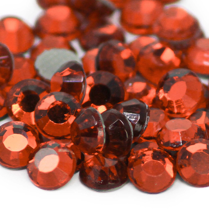 Red glass rhinestones with a faceted surface varying in size featuring a smooth backing and a shiny finish.