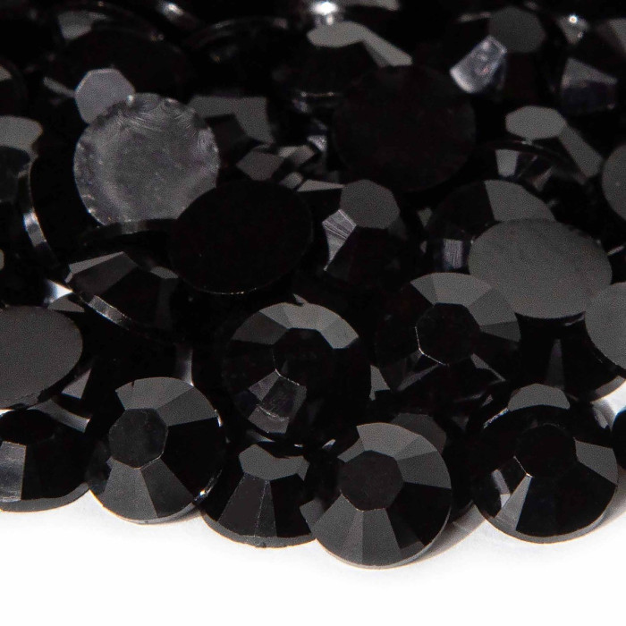Black faceted resin stones with a shiny surface and silver backing various sizes arranged closely together.