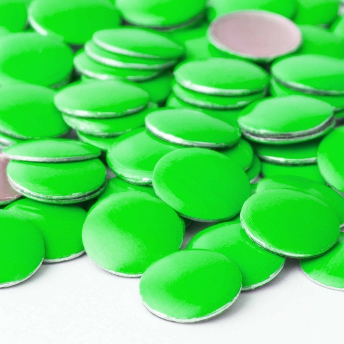 Neon green metal nailheads with a shiny surface and silver backing circular shape arranged in a scattered pattern.