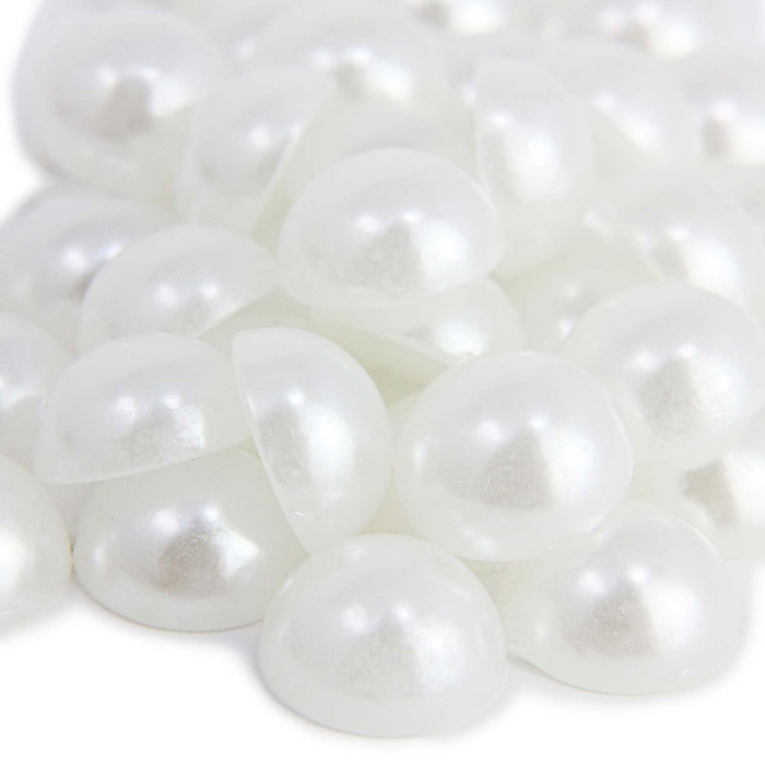 Flat back white pearls with a glossy finish semi-spherical shape and smooth texture arranged in a scattered pile.