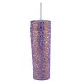 A tall silver tumbler covered in rhinestones with a clear straw and a smooth shiny surface. A tall silver tumbler covered in rhinestones with a clear straw and a smooth shiny surface.