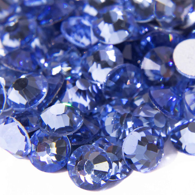 Machine cut crystal rhinestones in light sapphire blue round shape faceted surface with gray glue backing.