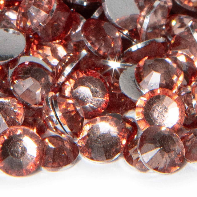 A pile of light rose resin stones with faceted surfaces and silver backing reflecting light and showing various sizes.