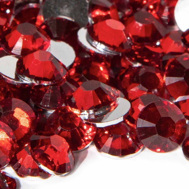Red resin rhinestones with faceted surfaces and silver backing varying in size reflecting light and creating sparkle.