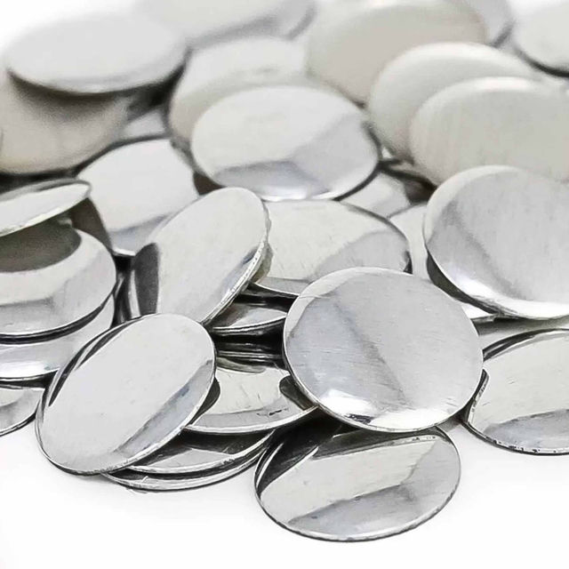 A pile of shiny silver metal nailheads round and flat with a smooth surface reflecting light without sparkling.
