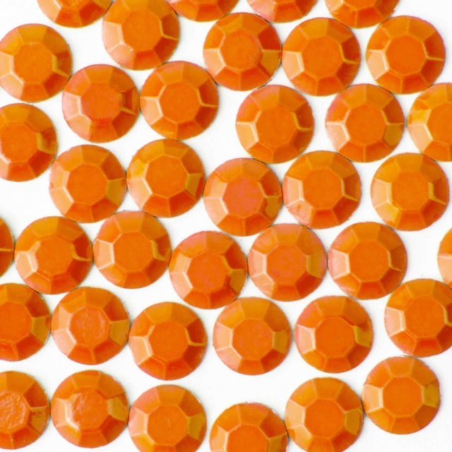 Neon orange machine-cut crystal rhinestones with faceted surfaces arranged closely together on a white background.