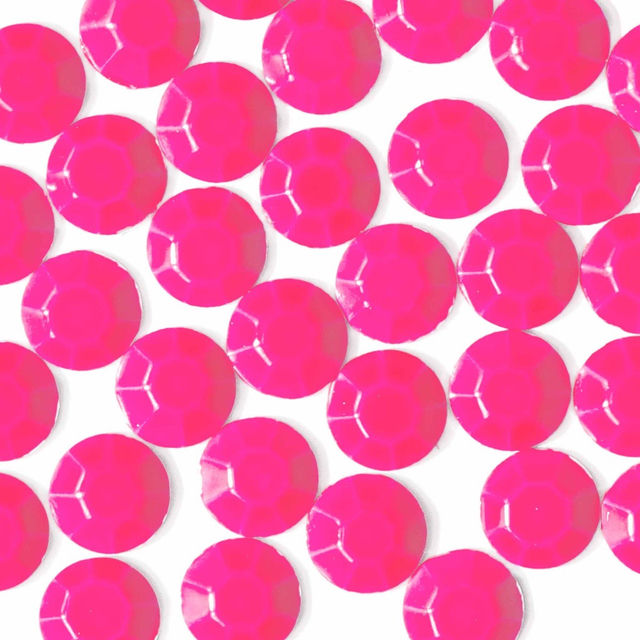 Neon pink machine-cut crystal rhinestones with a faceted surface glossy finish and circular shape arranged closely together.