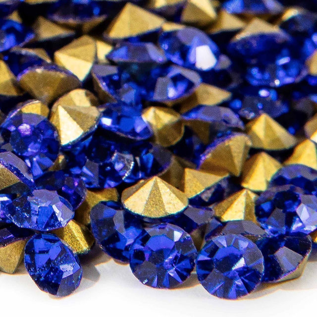A mix of deep blue round and pointed rhinestones with gold facets showcasing a shiny faceted surface and varying sizes.