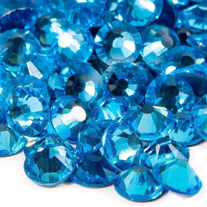 Aqua machine cut crystal rhinestones with faceted surfaces varying sizes and a glossy finish reflecting light in bright blue hues.