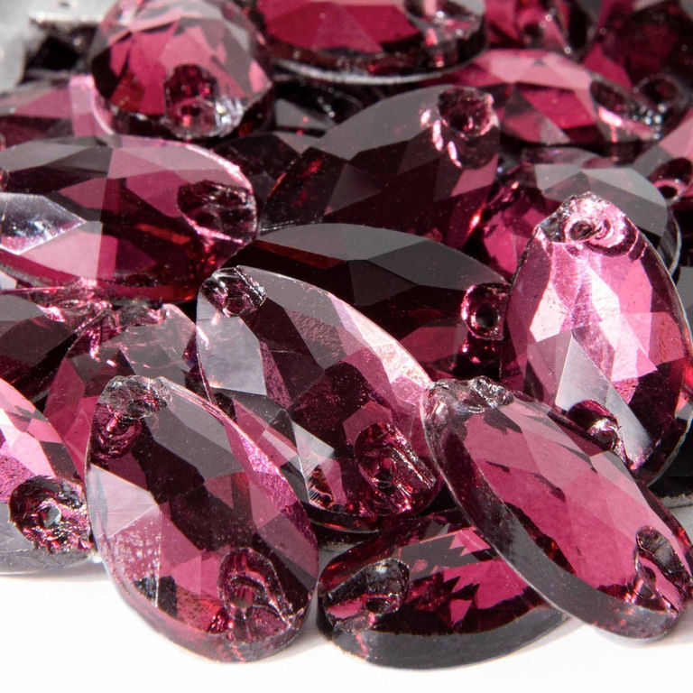 Teardrop-shaped rhinestones in shades of amethyst and deep pink with faceted surfaces and small sewing holes.