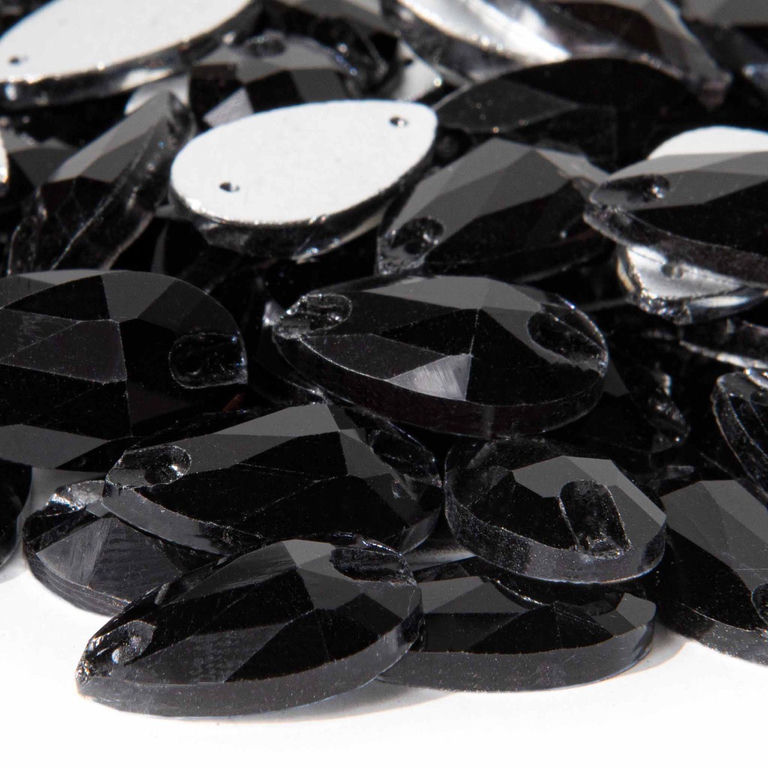 Black teardrop-shaped rhinestones with faceted surfaces and small sewing holes arranged in a scattered pile.
