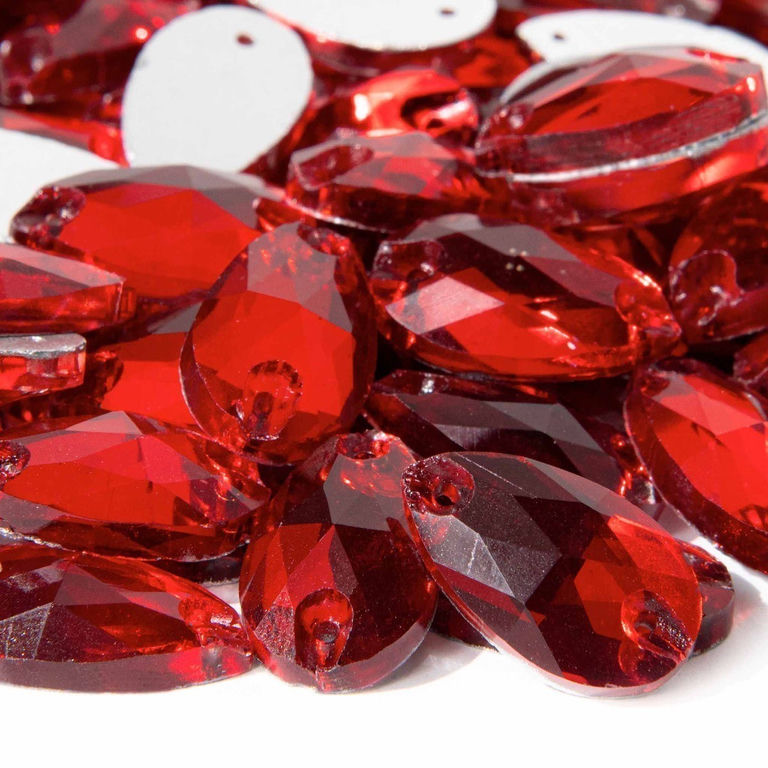 Red teardrop-shaped rhinestones with faceted surfaces and small holes for sewing arranged closely together.