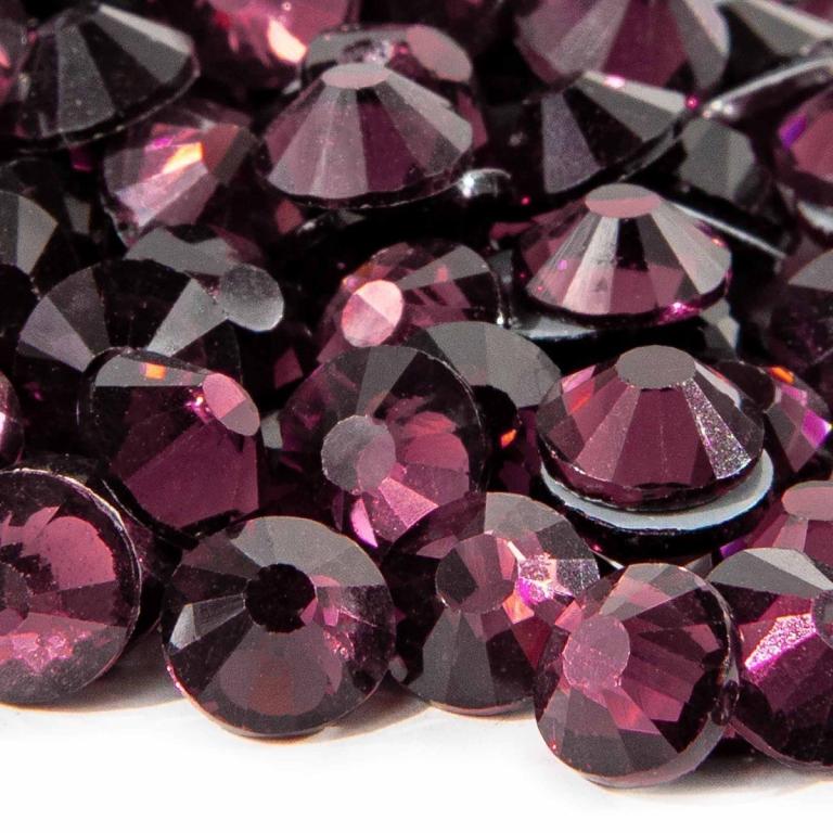 Machine cut crystal rhinestones in deep amethyst with faceted surfaces and gray glue backing varying in size and sparkle.