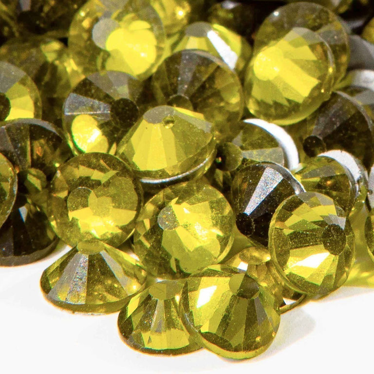 Machine cut crystal rhinestones in vibrant lime green with faceted surfaces and gray glue backing various sizes and shapes.