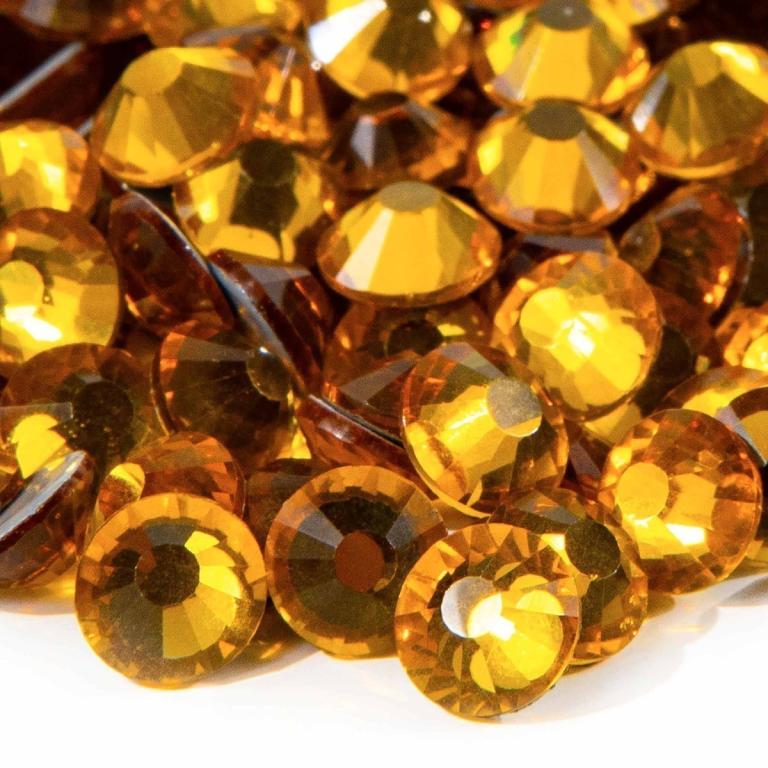 A&#x20;pile&#x20;of&#x20;topaz-colored&#x20;flatback&#x20;rhinestones&#x20;with&#x20;12-16&#x20;facets&#x20;featuring&#x20;a&#x20;shiny&#x20;silver&#x20;metal&#x20;backing.