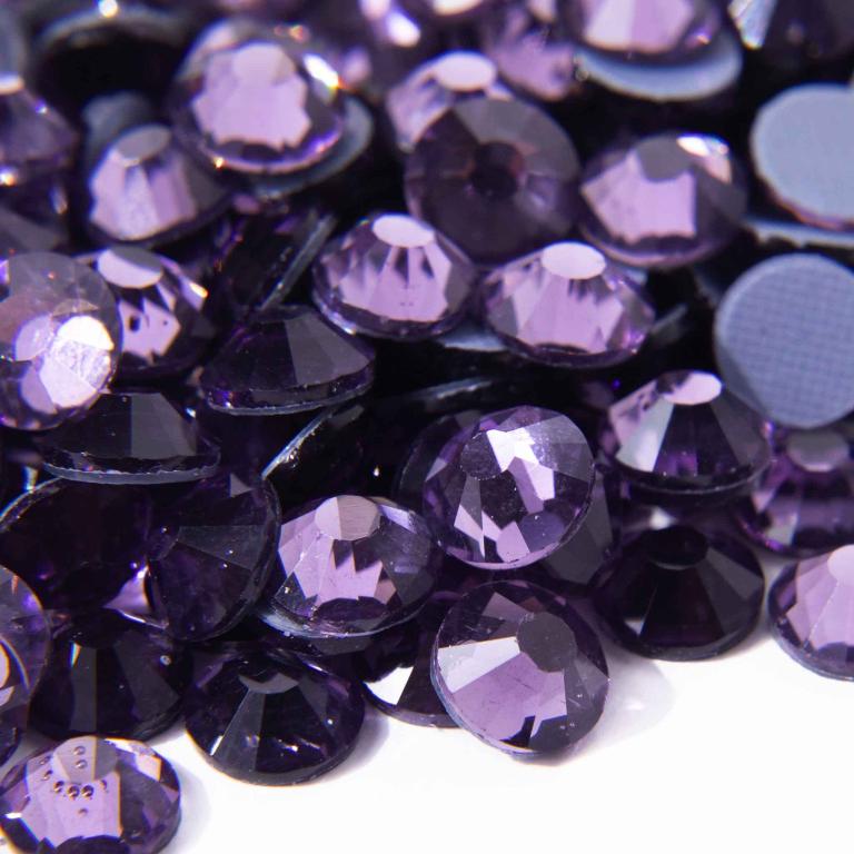 Purple machine cut crystal rhinestones with faceted surfaces and flat backs featuring a glossy finish and gray glue.