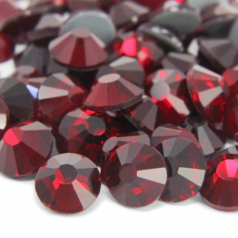 A&#x20;pile&#x20;of&#x20;dark&#x20;red&#x20;flatback&#x20;rhinestones&#x20;with&#x20;12-16&#x20;facets&#x20;and&#x20;a&#x20;silver&#x20;metal&#x20;backing&#x20;reflecting&#x20;light&#x20;and&#x20;showing&#x20;depth.
