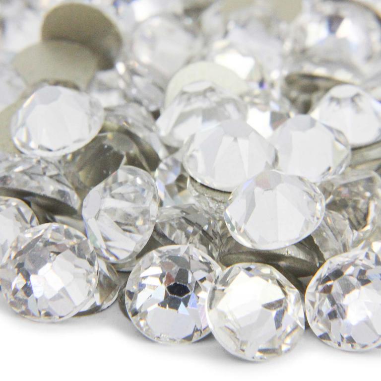 Clear machine-cut rhinestones with 14 facets featuring a shiny surface and a flatback design scattered in various orientations.