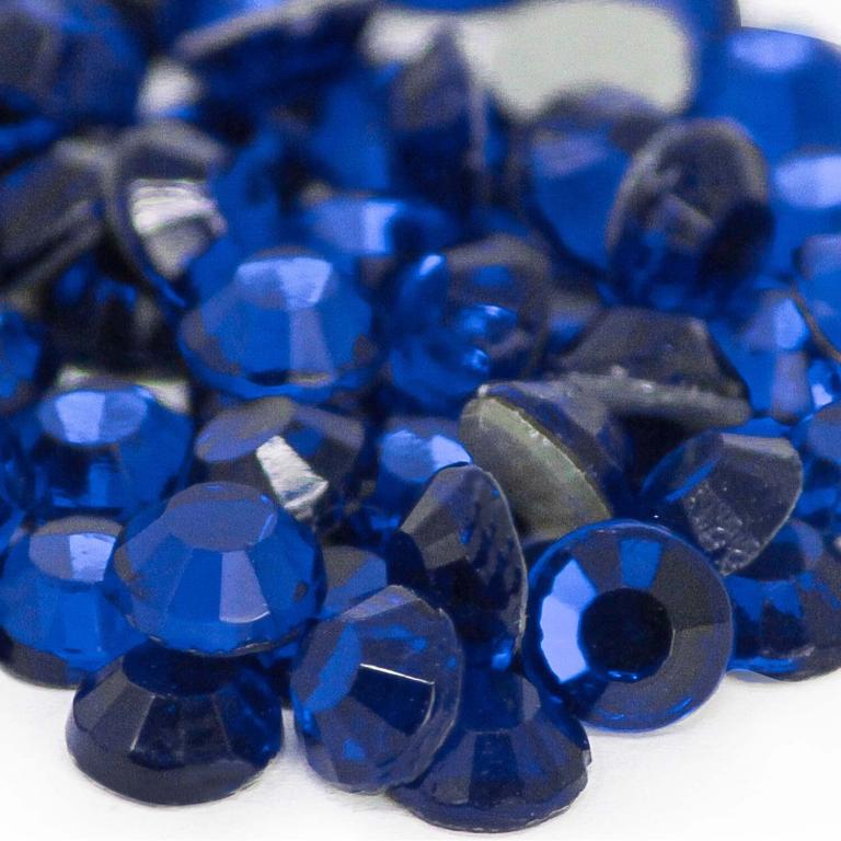 Machine cut crystal rhinestones in deep cobalt blue with faceted surfaces and gray glue backing.
