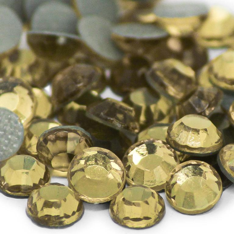 Machine cut crystal rhinestones in light topaz with faceted surfaces and gray glue backing varying sizes and slight color differences.