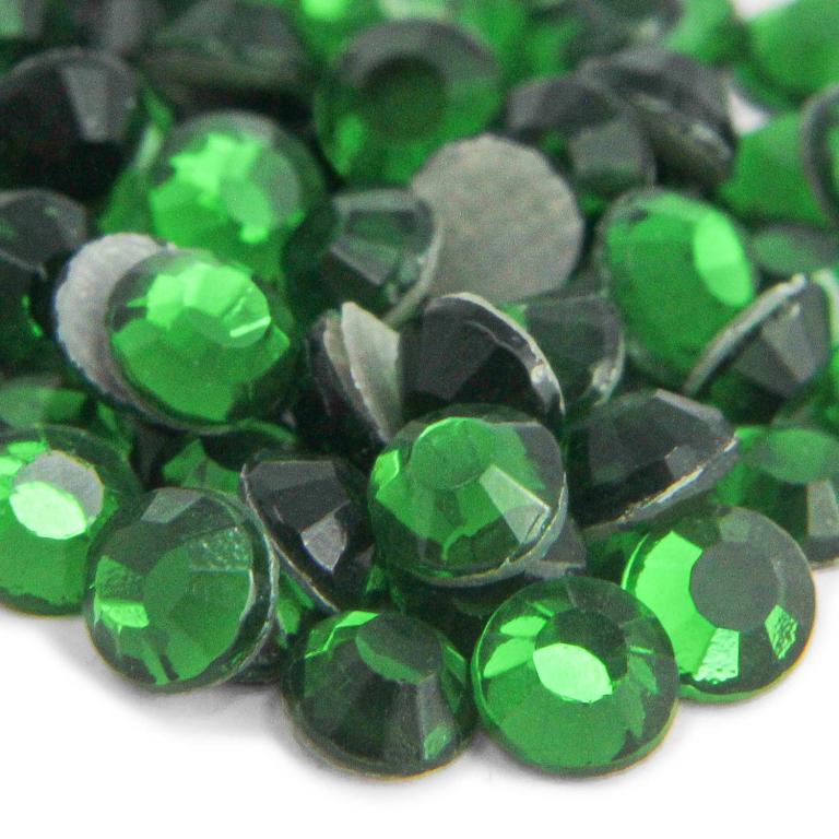 Green glass rhinestones with faceted surfaces some with silver glue backing varying in size and shape shiny finish.