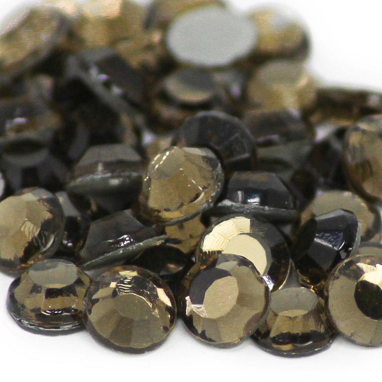 Machine cut crystal rhinestones in smoke topaz with faceted surfaces and gray glue backing varying in size and shape.