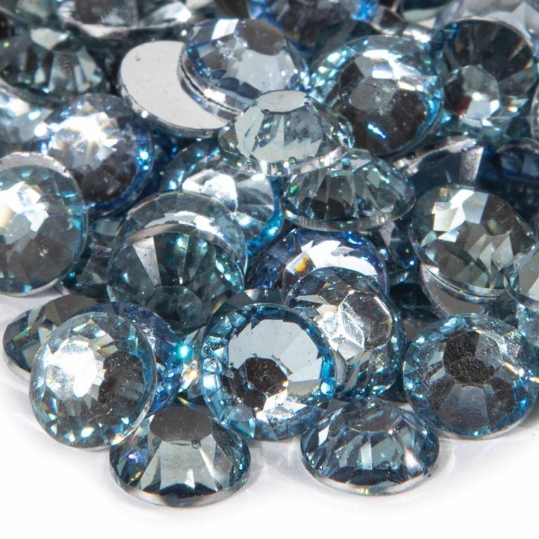A pile of light sapphire resin stones with faceted surfaces and silver backing reflecting light in shades of blue and clear.