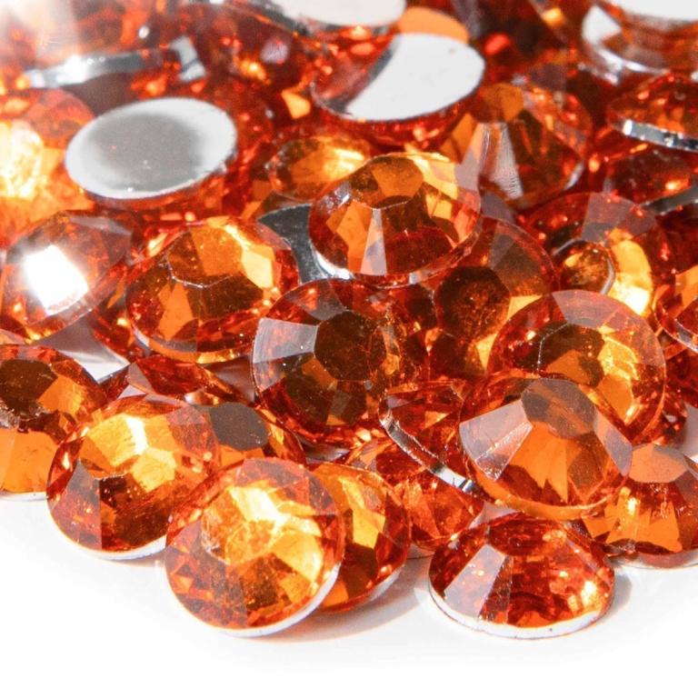Faceted orange resin stones with silver backing varying in size reflecting light with a sparkling finish.