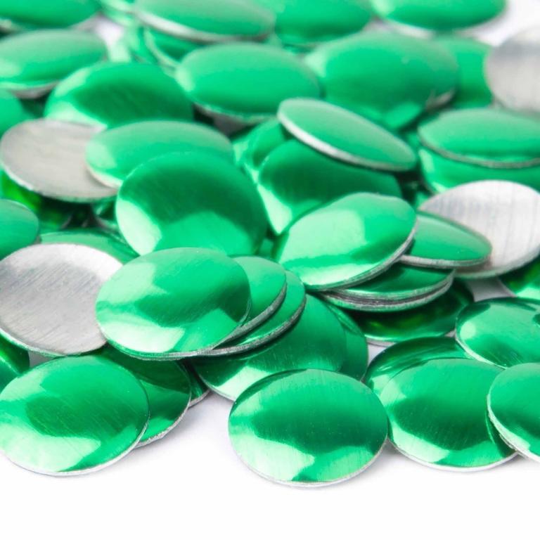 Shiny green metal nailheads with a smooth surface and silver backing arranged in a scattered pile.