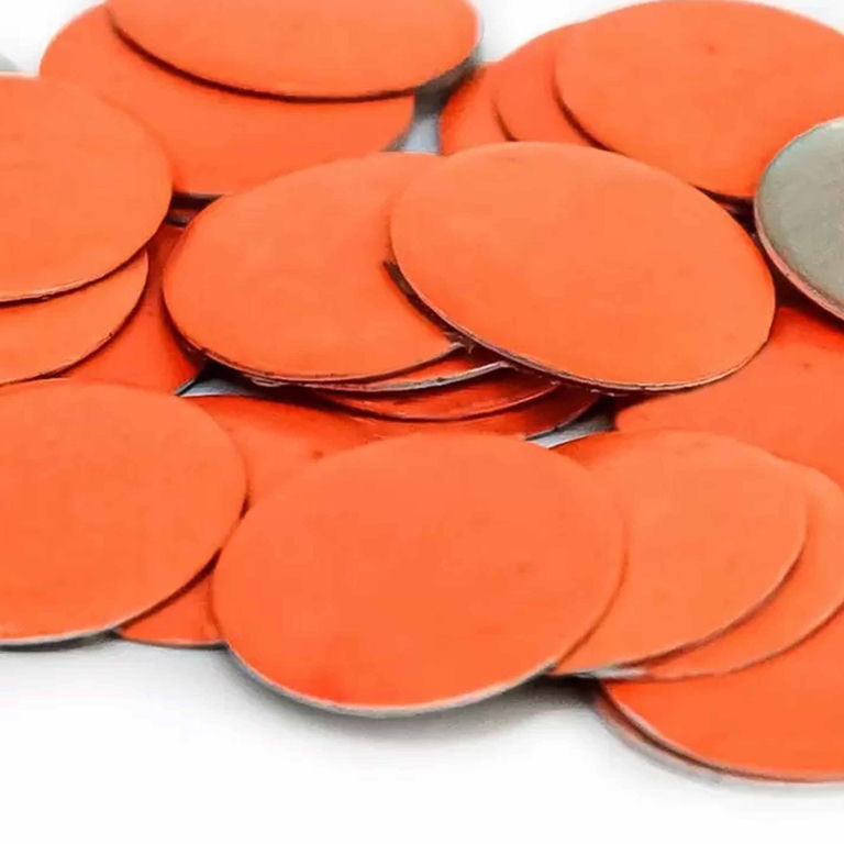 Neon orange flat circular metal nailheads with a smooth texture and silver backing arranged in a scattered pile.