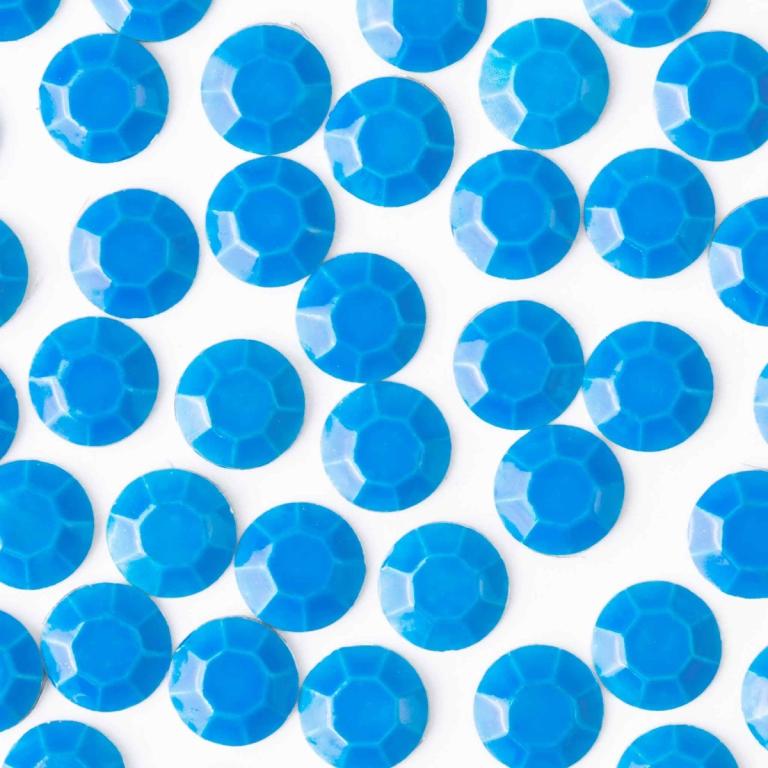Neon blue machine-cut crystal rhinestones with a faceted surface glossy finish and circular shape arranged on a white background.