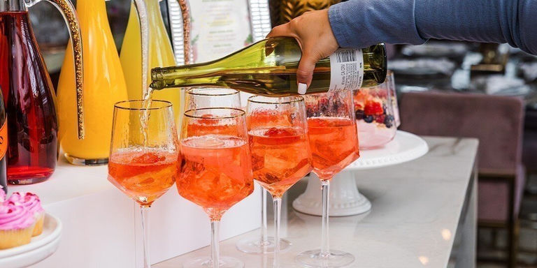 configuración de barra de mimosas para el Día de la Madre con garrafas de diamantes de imitación, jugo fresco y copas de champán