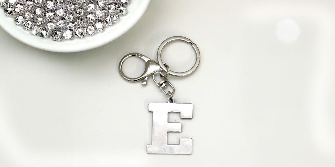 A&amp;&#x23;x20&#x3B;metal&amp;&#x23;x20&#x3B;keychain&amp;&#x23;x20&#x3B;with&amp;&#x23;x20&#x3B;letter&amp;&#x23;x20&#x3B;E&amp;&#x23;x20&#x3B;charm&amp;&#x23;x20&#x3B;and&amp;&#x23;x20&#x3B;rhinestones&amp;&#x23;x20&#x3B;displayed&amp;&#x23;x20&#x3B;on&amp;&#x23;x20&#x3B;white&amp;&#x23;x20&#x3B;surface
