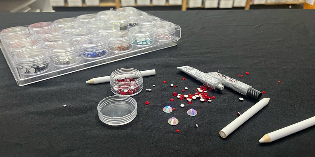 Crafting&amp;&#x23;x20&#x3B;table&amp;&#x23;x20&#x3B;with&amp;&#x23;x20&#x3B;rhinestones,&amp;&#x23;x20&#x3B;glue,&amp;&#x23;x20&#x3B;and&amp;&#x23;x20&#x3B;supplies&amp;&#x23;x20&#x3B;organized&amp;&#x23;x20&#x3B;for&amp;&#x23;x20&#x3B;a&amp;&#x23;x20&#x3B;DIY&amp;&#x23;x20&#x3B;Valentine