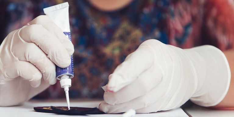 Persona con guantes aplicando pegamento a tela para manualidades con diamantes de imitación