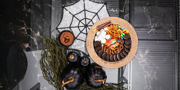 vista aérea de un tablero de golosinas de Halloween con estilo glamoroso con plato cargador de pedrería y dulces coloridos