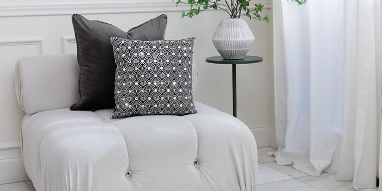 modern white accent chair with velvet and rhinestone pillows in natural light nook
