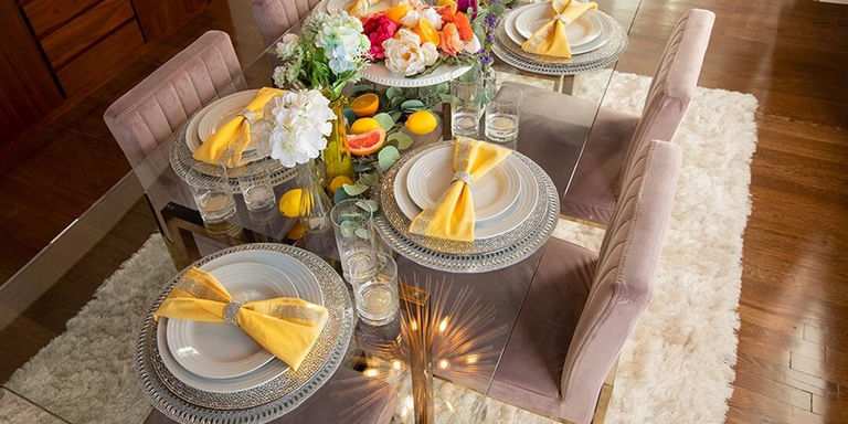 mesa de primavera soleada con servilletas amarillas, cítricos frescos y florales suaves estilizados en una mesa de espejo